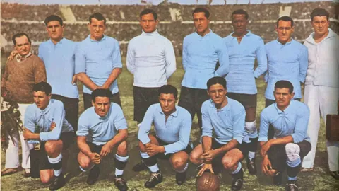 The Uruguay squad in light-blue shirts, one row standing and one crouching, in a team photograph.
